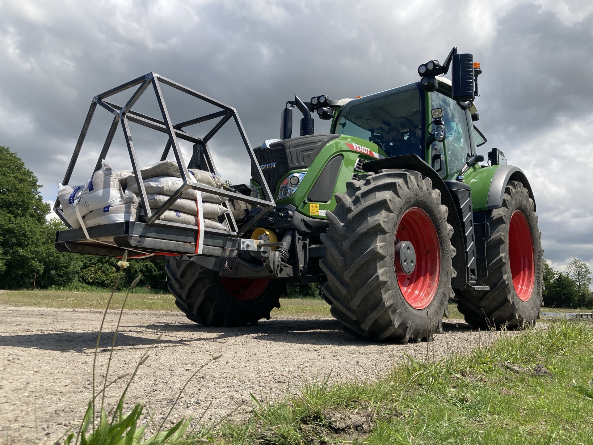 A tractor carrying a fabricated steel frame loaded with bags.