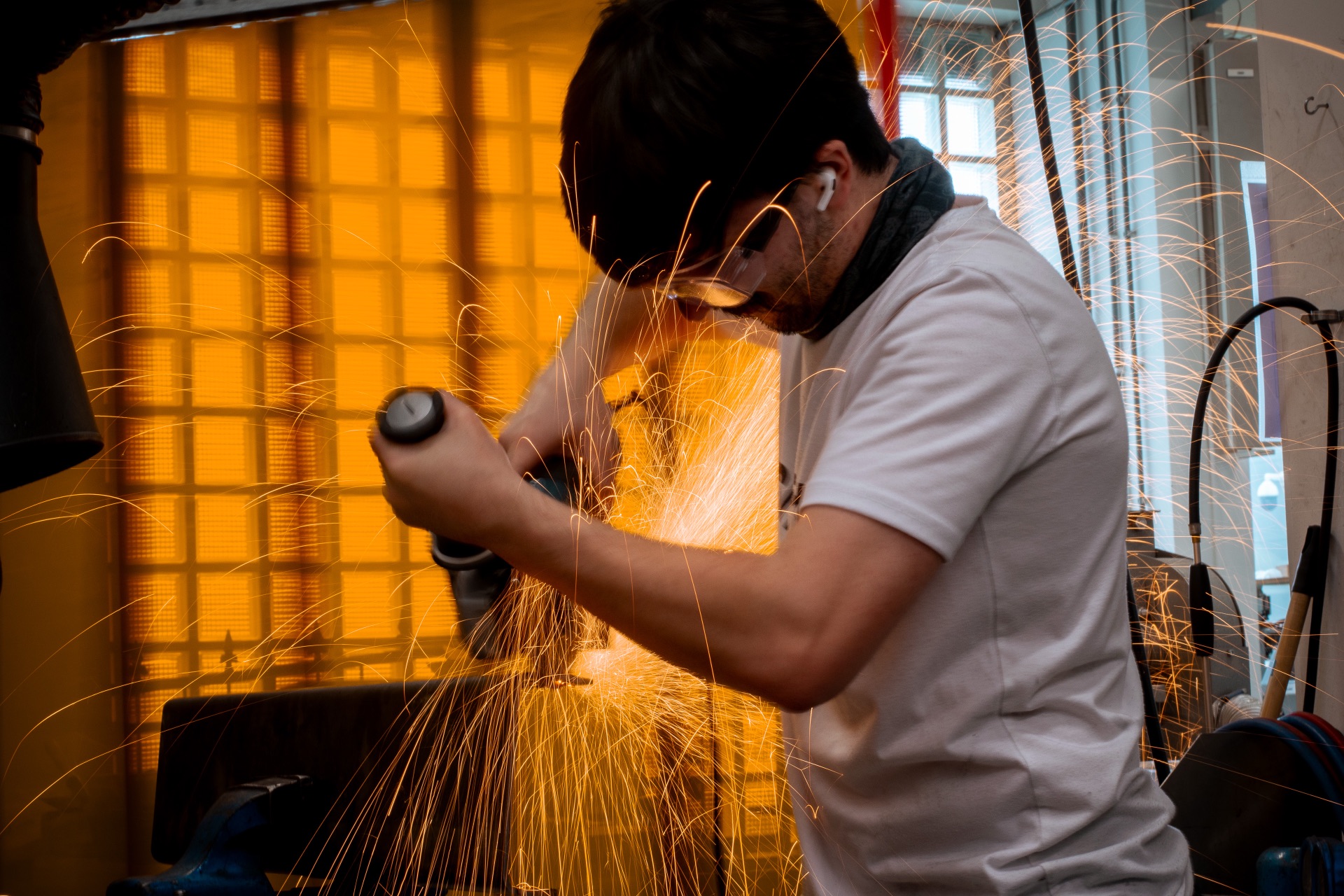 Evren grinding metal in the workshop, with sparks flying.